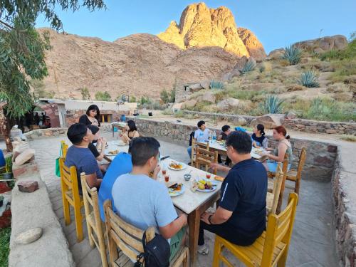 a group of people sitting at a table eating food at Fox Camp (Moses Lodge) in Saint Catherine
