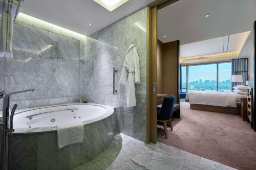 ein Badezimmer mit einer Badewanne und ein Schlafzimmer mit einem Bett in der Unterkunft Hilton Manila in Manila