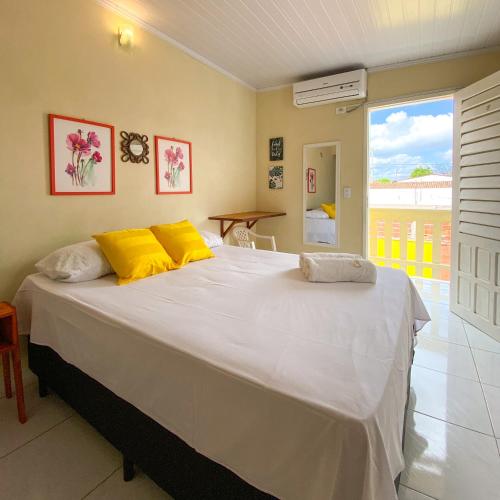 a bedroom with a large white bed with yellow pillows at Encanto do Sol Hospedagem in Icaraí