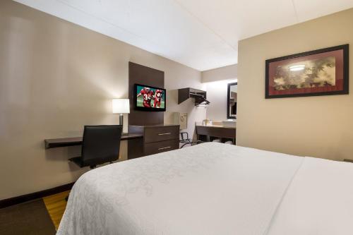 a hotel room with a bed and a desk with a computer at Red Roof Inn PLUS+ Nashville Airport in Nashville