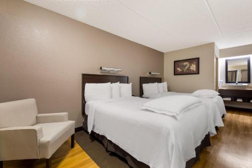 a room with two beds and a chair in it at Red Roof Inn PLUS+ Nashville Airport in Nashville