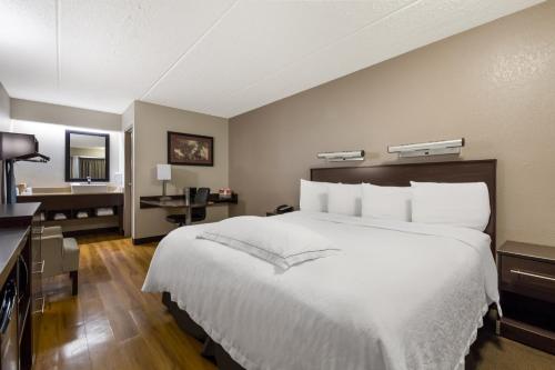 um quarto com uma grande cama branca e uma secretária em Red Roof Inn PLUS+ Nashville Airport em Nashville