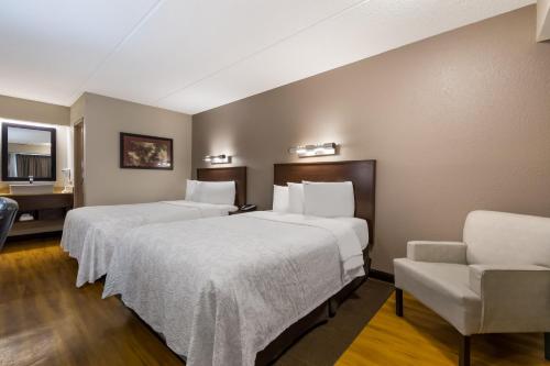 a hotel room with two beds and a chair at Red Roof Inn PLUS+ Nashville Airport in Nashville