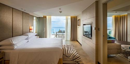 バトゥ・フェリンギにあるダブルツリー リゾート バイ ヒルトン ホテル ペナンの大きなベッドとバルコニーが備わるホテルルームです。