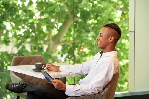 a man sitting at a table with a cup of coffee at Doubletree By Hilton Perth Northbridge in Perth