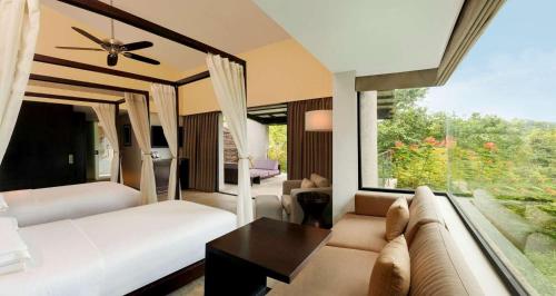 a bedroom with two beds and a couch and a window at Hilton Shillim Estate Retreat and Spa in Lonavala