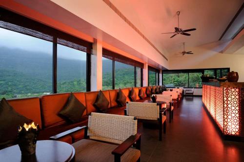 a restaurant with tables and chairs and large windows at Dharana at Shillim All Inclusive Luxury Wellness Retreat in Lonavala
