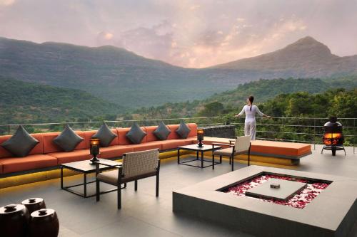 a woman standing on a balcony with a view of mountains at Dharana at Shillim All Inclusive Luxury Wellness Retreat in Lonavala