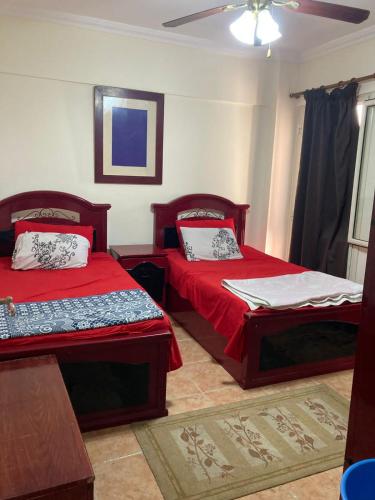 a bedroom with two beds with red sheets and a ceiling at Chalet For rent at Nice 2 North Coast, شالية للاجار في نيس ٢ الساحل الشمالي in El Hamam