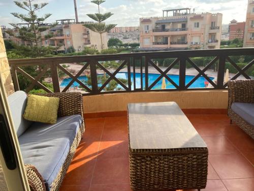 a balcony with chairs and a table and a view of a pool at Chalet For rent at Nice 2 North Coast, شالية للاجار في نيس ٢ الساحل الشمالي in El Hamam