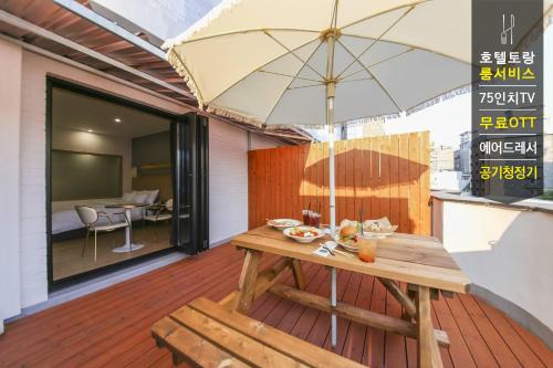 a wooden table with an umbrella on a patio at Hotel Torang Jeonju in Jeonju