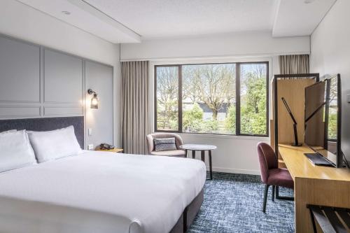 a hotel room with a bed and a desk and a window at Chateau On The Park - Christchurch, A Doubletree By Hilton in Christchurch