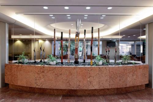 a lobby with a counter with plants and candles at DoubleTree by Hilton Esplanade Darwin in Darwin