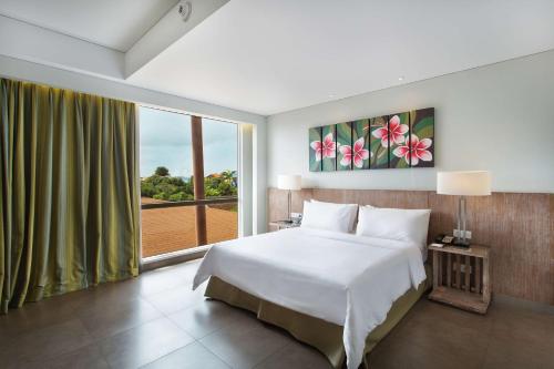 a bedroom with a large bed and a large window at Hilton Garden Inn Bali Ngurah Rai Airport in Kuta