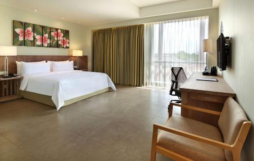 a bedroom with a bed and a desk and a television at Hilton Garden Inn Bali Ngurah Rai Airport in Kuta