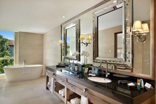 La salle de bains est pourvue d'une baignoire et d'un grand miroir. dans l'établissement Hilton Garden Inn Bali Ngurah Rai Airport, à Kuta