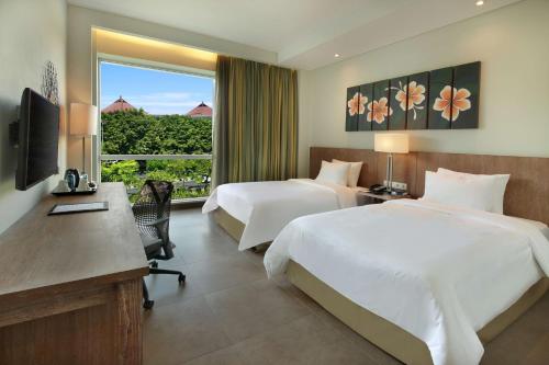 a hotel room with two beds and a desk and a window at Hilton Garden Inn Bali Ngurah Rai Airport in Kuta