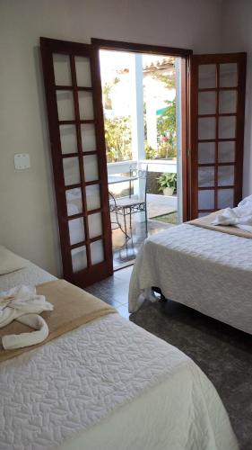 1 dormitorio con 2 camas y puerta con patio en Pousada Paraíso do Atlântico, en Arraial do Cabo
