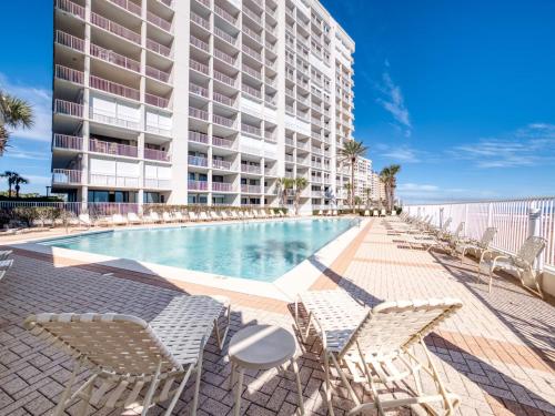 a swimming pool with chairs and a building at Pelican Pointe 1505 by Vacation Homes Collection in Orange Beach