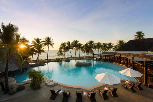 uma grande piscina junto ao oceano com palmeiras em DoubleTree by Hilton Fiji - Sonaisali Island em Nadi