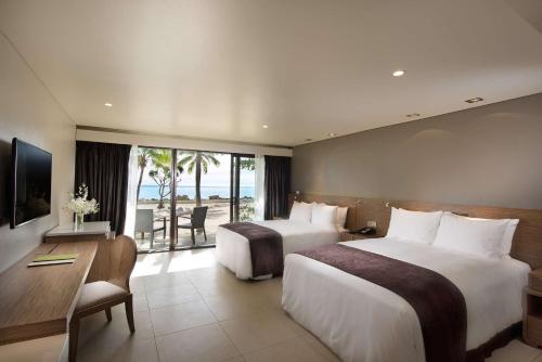 Habitación de hotel con 2 camas, escritorio y TV. en DoubleTree by Hilton Fiji - Sonaisali Island en Nadi