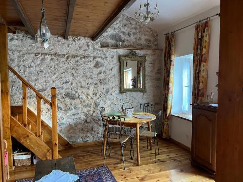 a dining room with a table and a stone wall at BASIA, Lourdes - centre , quartier historique Sanctuaires a 7 min a pied in Lourdes