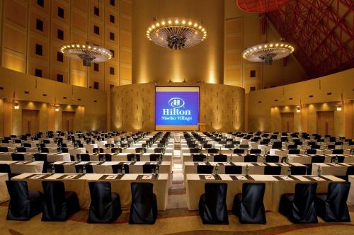 a large room with a stage with chairs and a screen at Hilton Niseko Village in Niseko