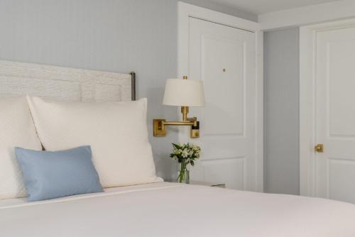 a white bed with a blue pillow and a lamp at The Oaks Waterfront Hotel in Saint Michaels