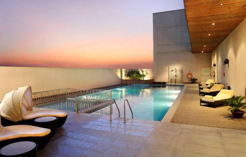 a pool in a hotel with chairs and a couch at DoubleTree by Hilton Gurgaon New Delhi NCR in Gurgaon