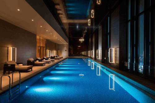 ein großer Pool in einem Hotel mit Sofas und Stühlen in der Unterkunft Conrad Osaka in Osaka