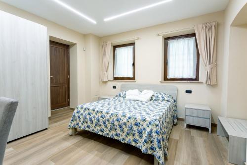 a bedroom with a bed and two windows at Residence la Sorgiva in Pollone