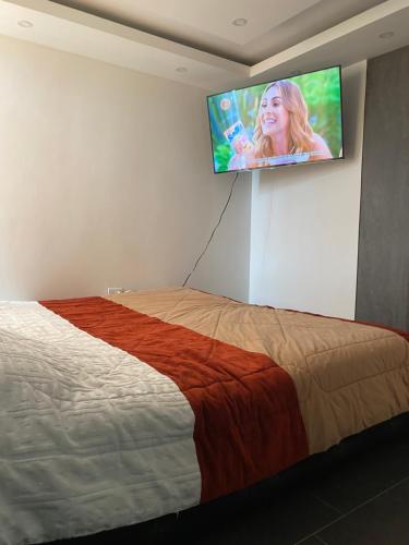 - une chambre avec un lit et une télévision murale à écran plat dans l'établissement Apartamento en ipiales nariño, cerca a la frontera con ecuador, à Ipiales
