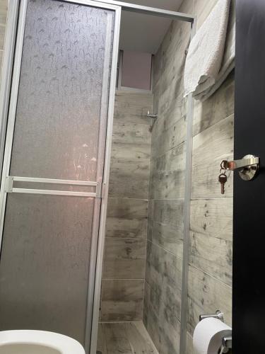 La salle de bains est pourvue d'une douche avec une porte en verre. dans l'établissement Apartamento en ipiales nariño, cerca a la frontera con ecuador, à Ipiales