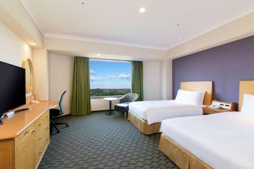 a hotel room with two beds and a flat screen tv at Hilton Tokyo Narita Airport in Narita