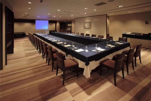 a long table in a room with chairs and a screen at Hilton Tokyo Narita Airport in Narita