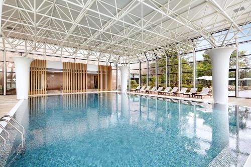 - une grande piscine avec des chaises dans un bâtiment dans l'établissement Hilton Gyeongju, à Gyeongju