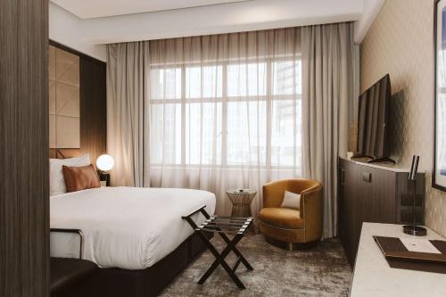 um quarto de hotel com uma cama e uma cadeira e uma janela em Doubletree By Hilton Wellington em Wellington