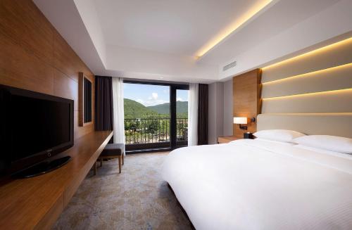 sypialnia z dużym białym łóżkiem i dużym oknem w obiekcie Hilton Gyeongju w mieście Gyeongju