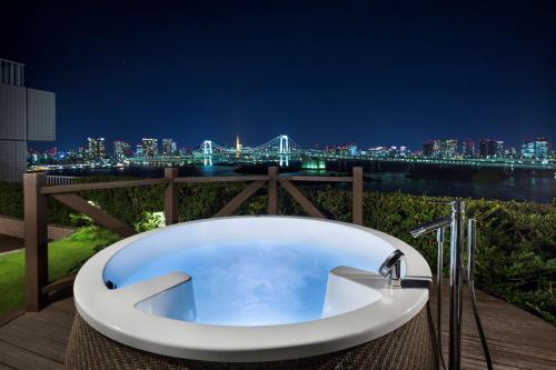 a bath tub with a view of the city at night at Hilton Tokyo Odaiba in Tokyo