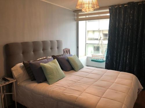 - une chambre avec un grand lit, des oreillers et une fenêtre dans l'établissement Pacific Ocean Penthouse, à Lima