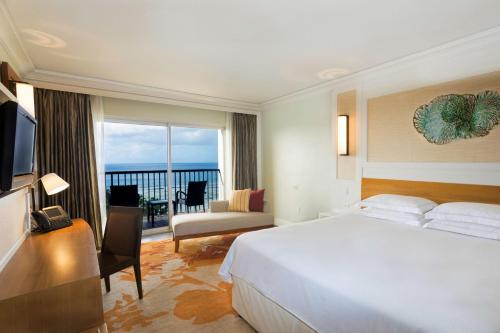 a hotel room with a large bed and a balcony at Hilton Guam Resort & Spa in Tumon