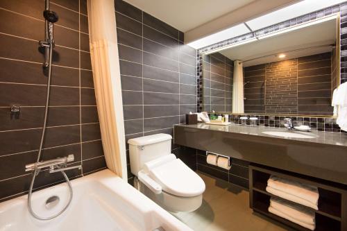 a bathroom with a toilet and a sink and a tub at Hilton Guam Resort & Spa in Tumon