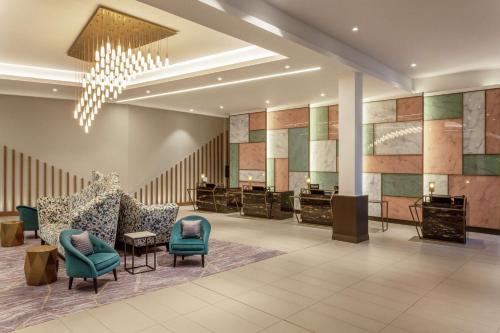 a lobby with chairs and tables and a chandelier at Hilton Aberdeen TECA in Aberdeen