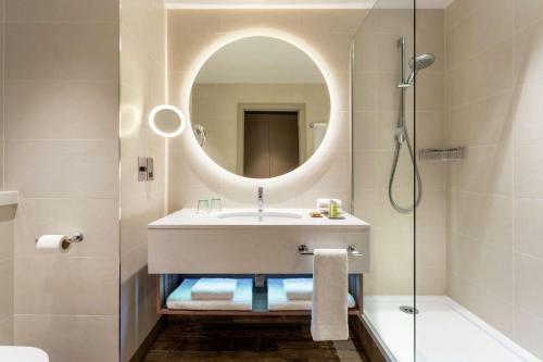a bathroom with a sink and a mirror and a shower at Hilton Aberdeen TECA in Aberdeen