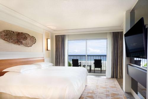 a bedroom with a large white bed and a large window at Hilton Guam Resort & Spa in Tumon