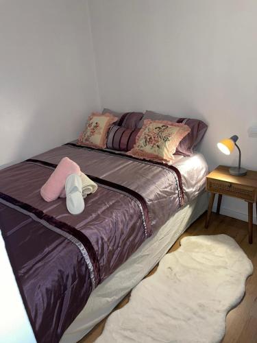 a bedroom with a large bed with purple sheets and pillows at Stunning 2 bedroom green view house in Thamesmead