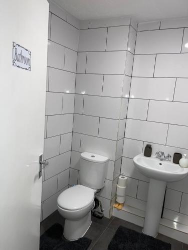 a white bathroom with a toilet and a sink at Stunning 2 bedroom green view house in Thamesmead