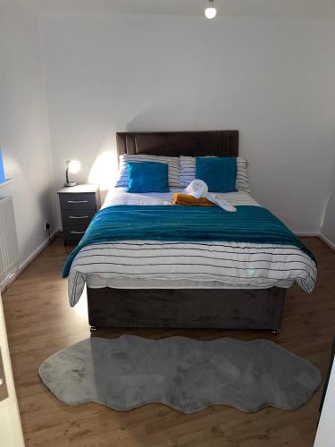 a bedroom with a large bed with blue pillows at Stunning 2 bedroom green view house in Thamesmead