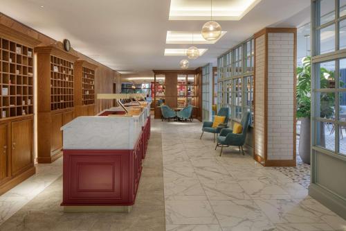 une bibliothèque avec une île rouge dans une pièce avec des chaises dans l'établissement DoubleTree by Hilton Bath, à Bath