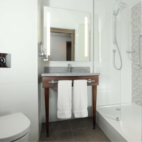 a bathroom with a sink and a toilet and a mirror at Hampton By Hilton Belfast City Centre in Belfast
